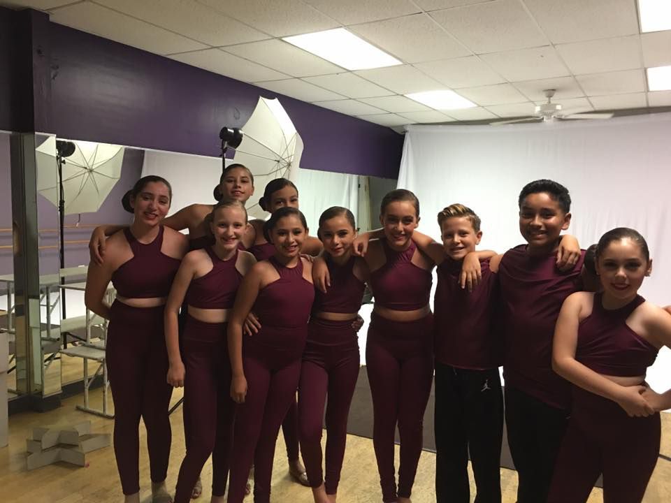 A group of young people are posing for a picture in a dance studio.