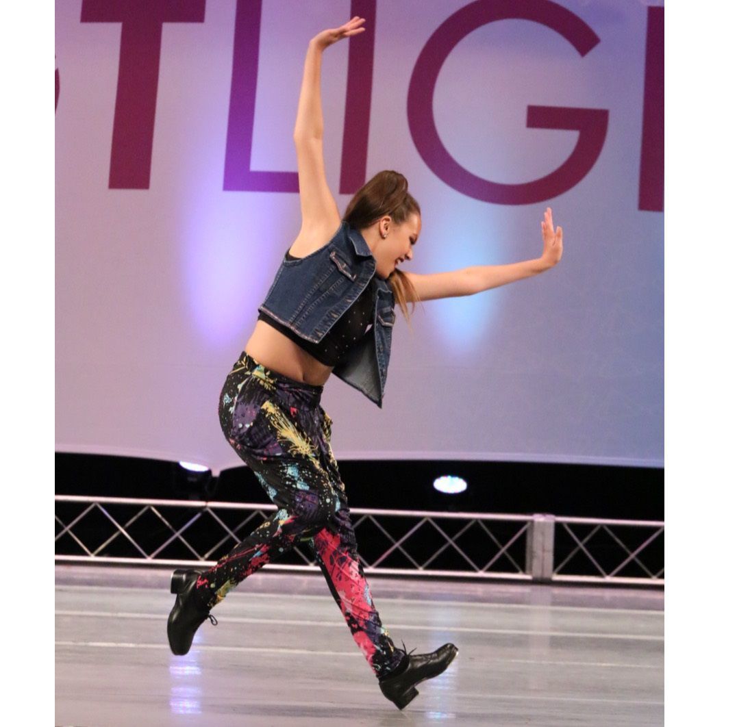 A woman is dancing in front of a sign that says tligi