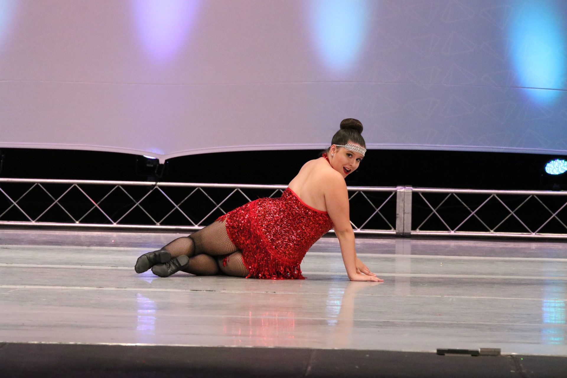 A woman in a red dress is kneeling on the floor on a stage.