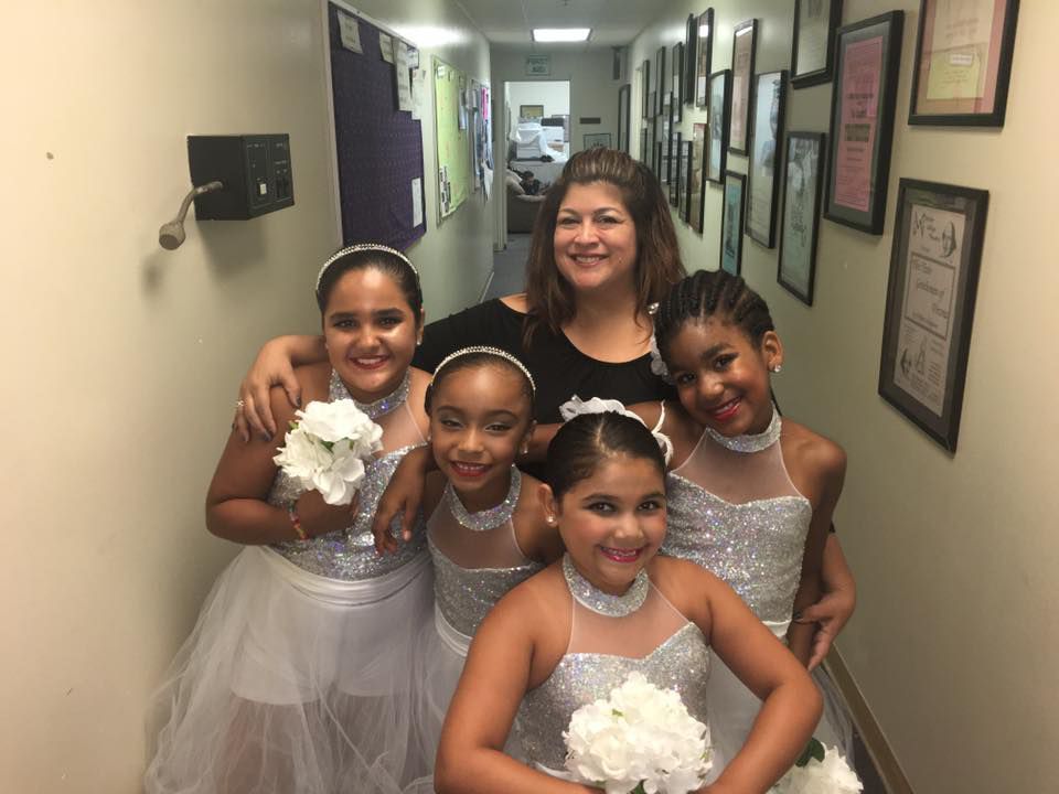 A group of young girls are posing for a picture in a hallway.