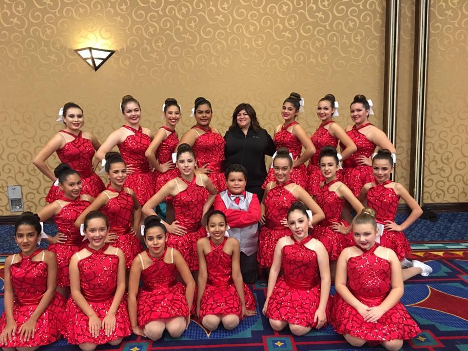 A group of young girls in red dresses are posing for a picture.