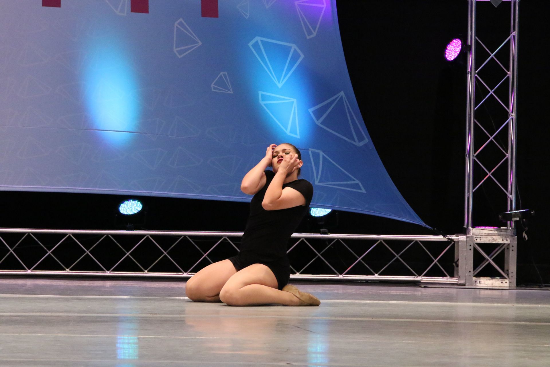 A woman is kneeling down on the floor on a stage.