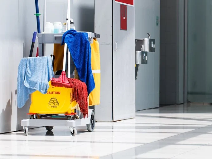 A cleaning cart with a mop and towels in a hallway.