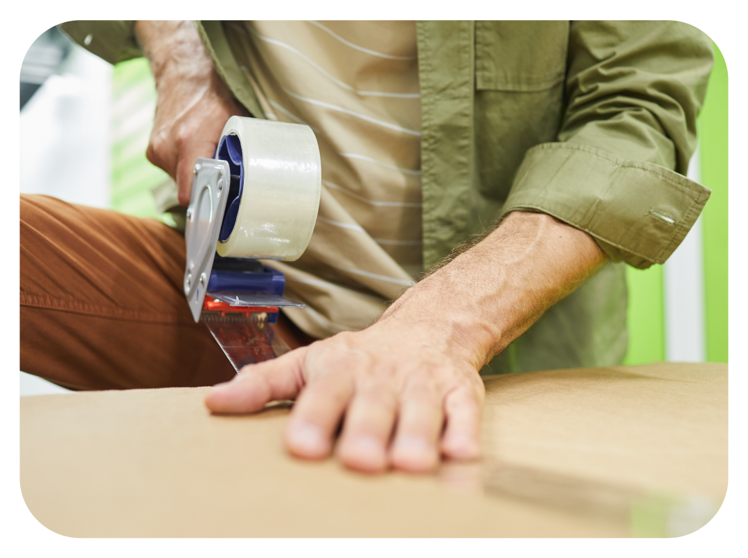 Person paying online with credit card, while couple holds moving box.