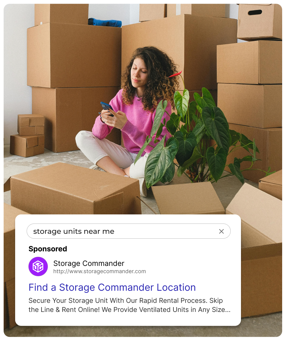 Woman using phone surrounded by boxes, advert for Storage Commander.