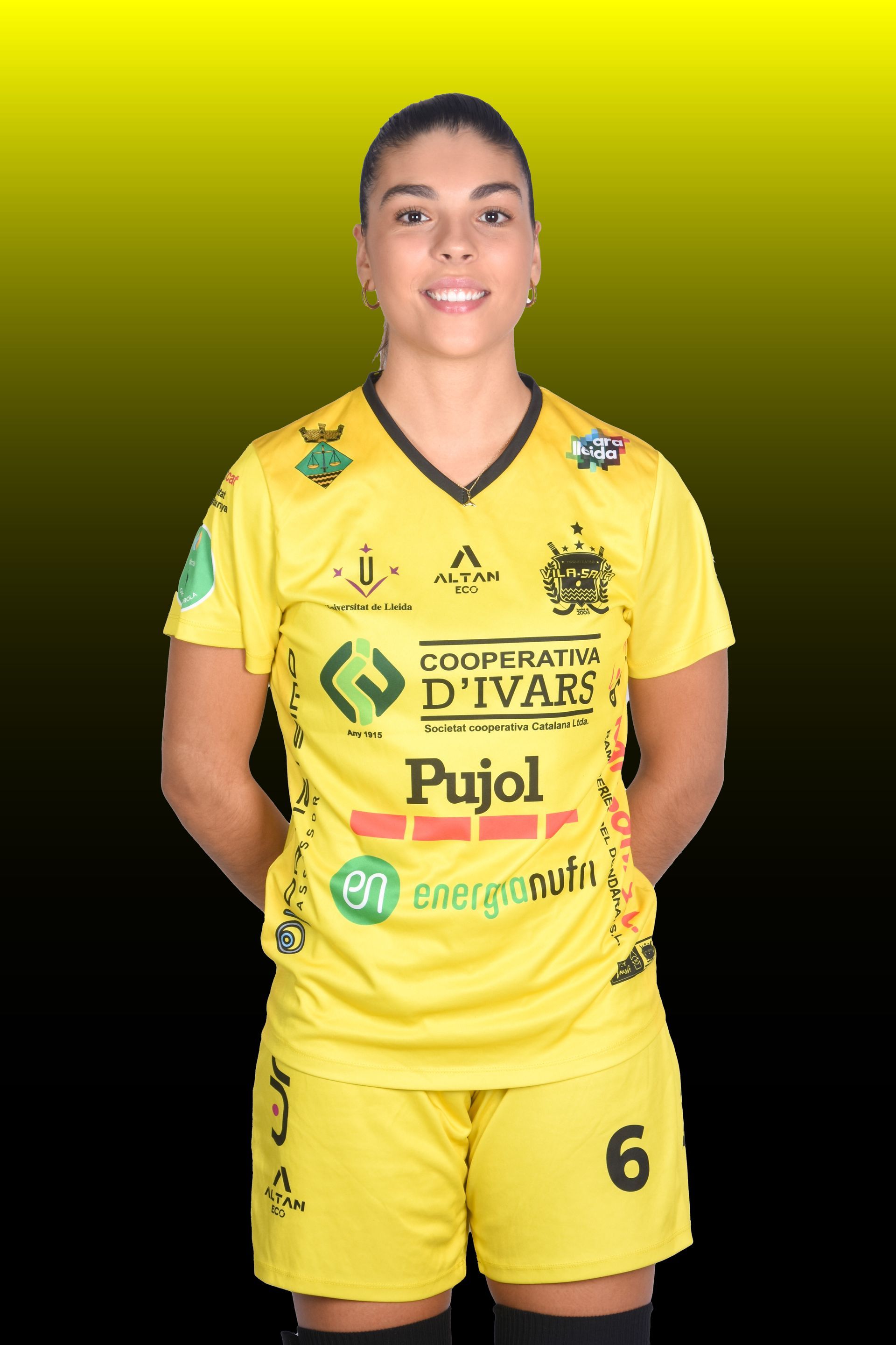 Mujer con camiseta amarilla, número 6, jugando a hockey sobre patines, en un estadio.