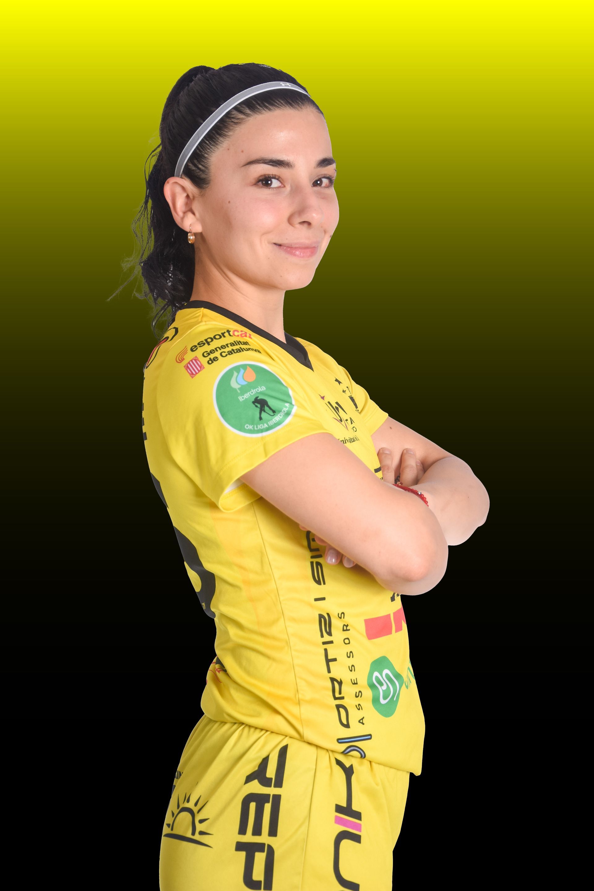 Una mujer con camiseta amarilla sonríe, apoyada en una barrera. Se ve el logo de la Cooperativa D'Ivars.