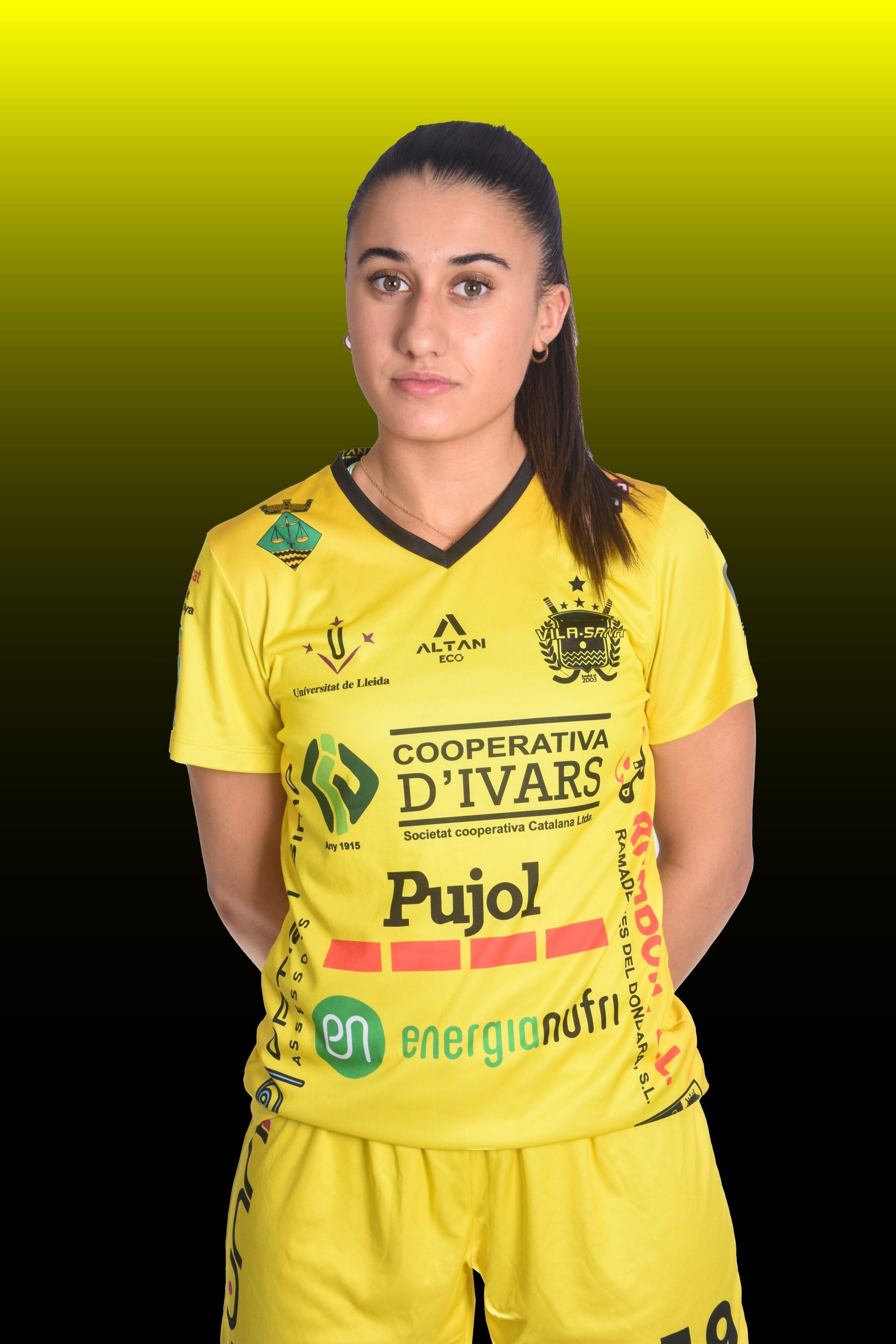 Mujer en patines, palo de hockey, camiseta española; lista para golpear la pelota en la cancha.