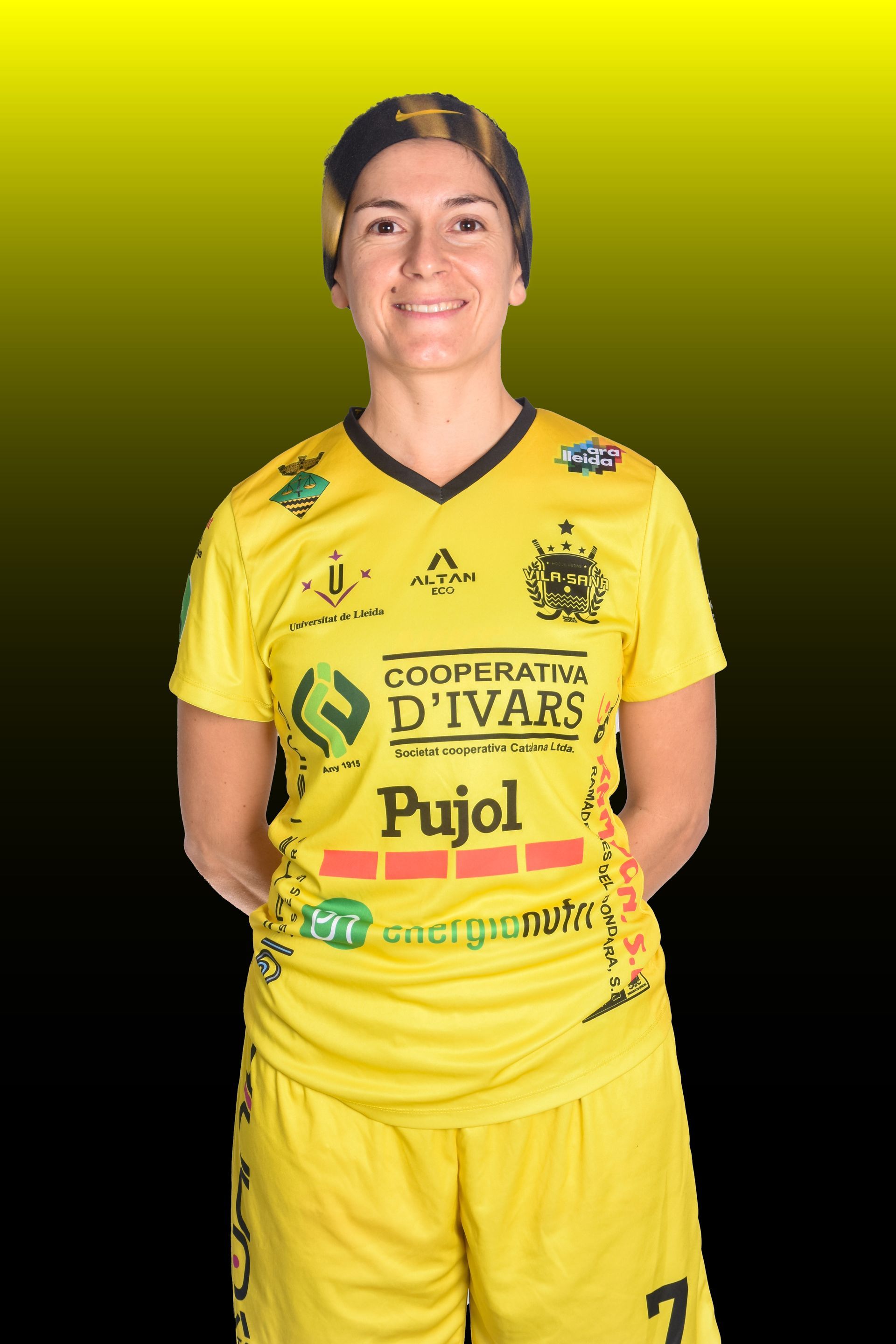 Mujer con uniforme amarillo de hockey sobre patines, con los brazos en alto en señal de celebración, saltando. Palo de hockey, pista cubierta.