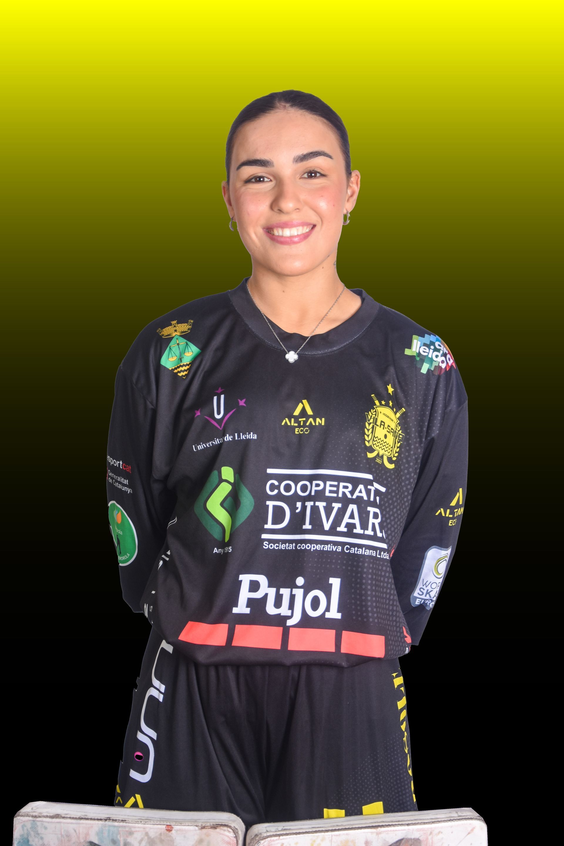 Una mujer con casco de hockey sonríe, vistiendo una camiseta; fondo de piso de madera.