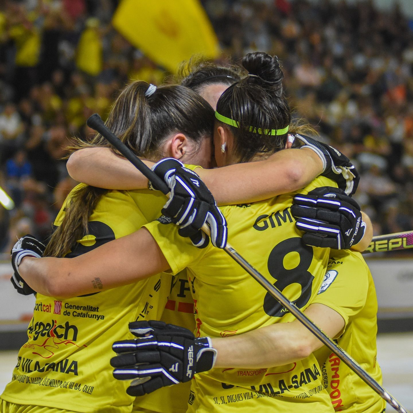 Tres mujeres con camisetas amarillas se abrazan en una pista, celebrando una victoria de hockey.