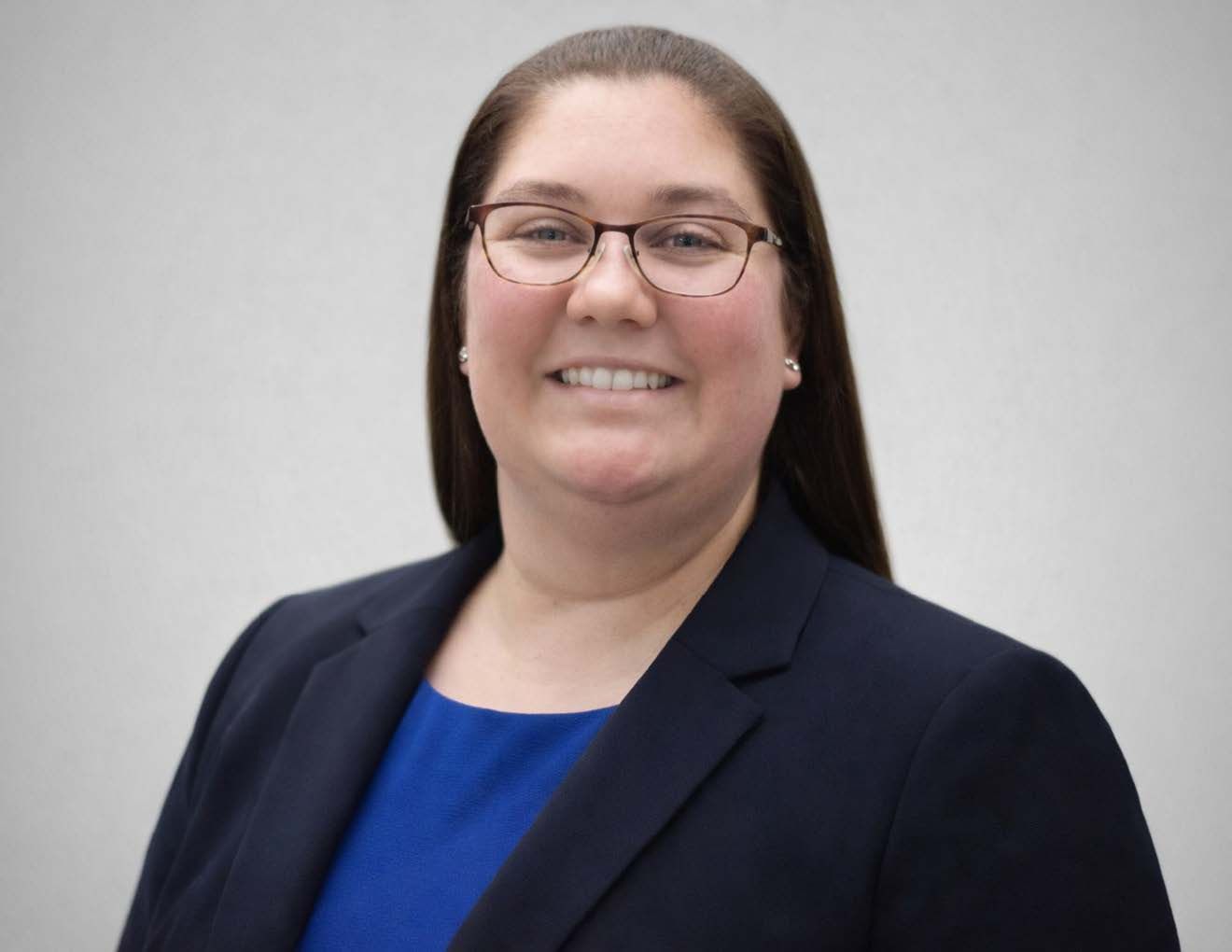 A woman is sitting at a desk with a laptop and a vase of flowers.