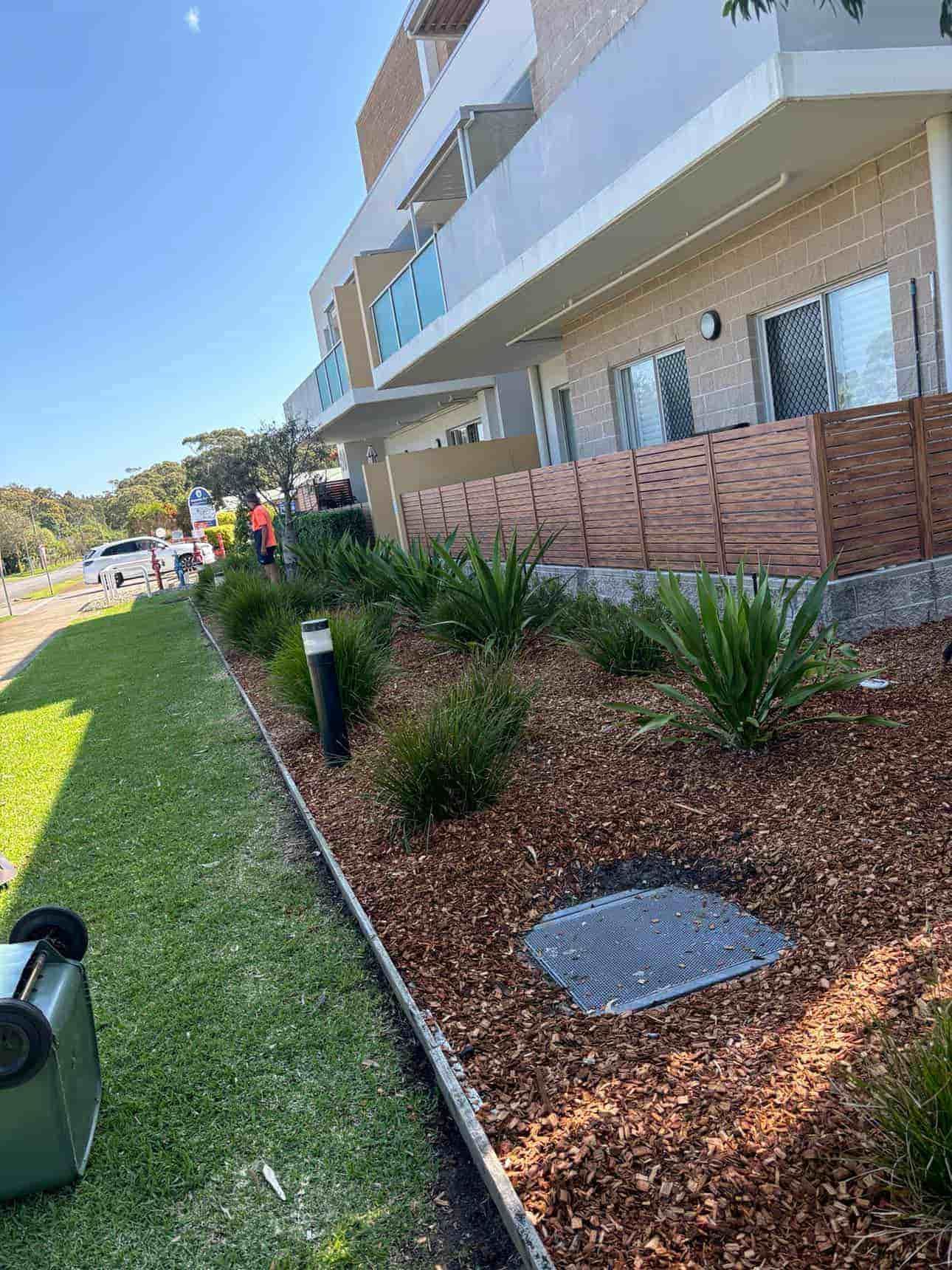 A Large Building With A Lot Of Plants In Front Of It — Gibbo’s Lawns & Property Maintenance In Salamander Bay, NSW
