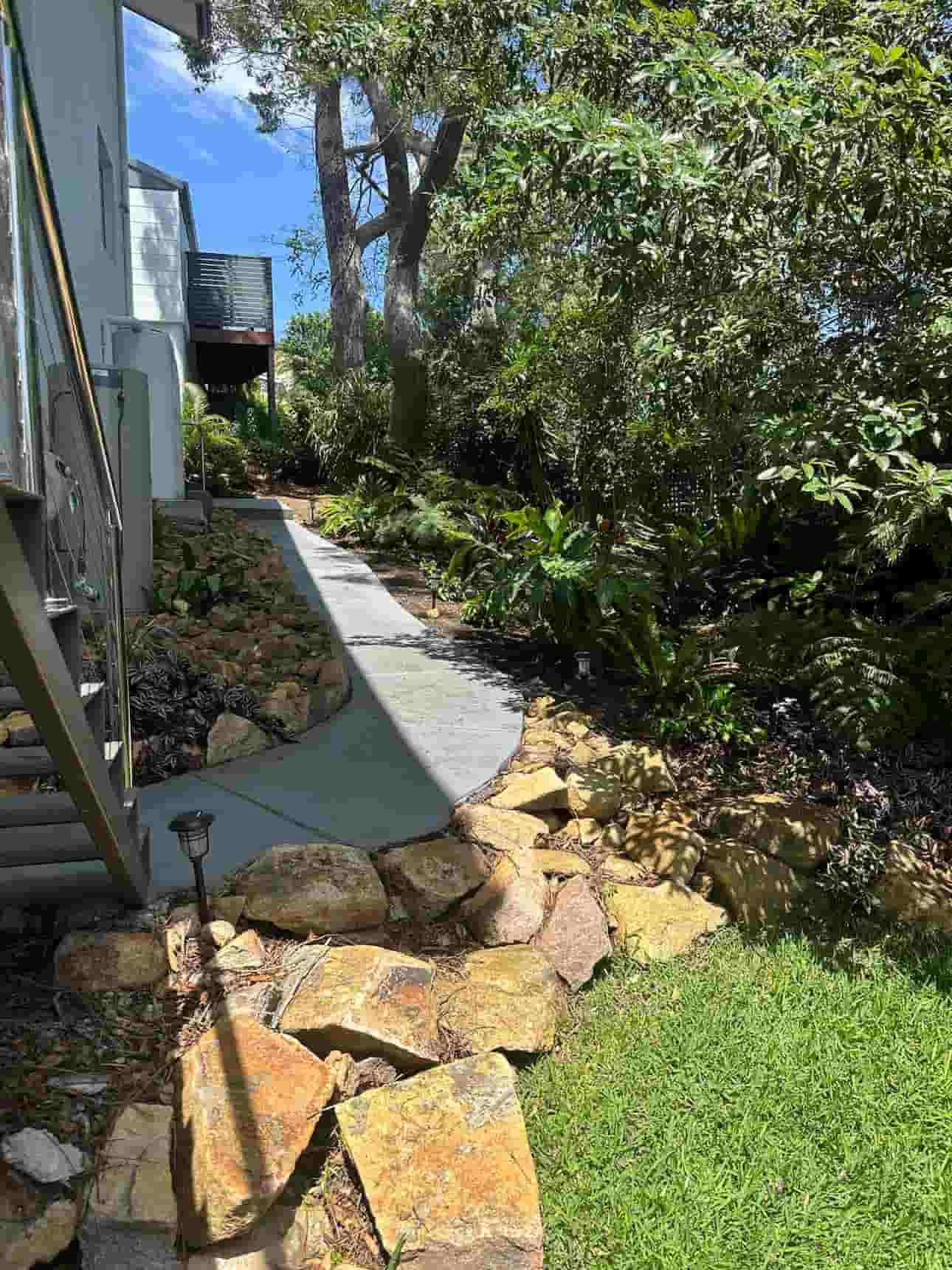 A Stone Walkway Leading To A House Surrounded By Trees And Grass — Gibbo’s Lawns & Property Maintenance In Nelson Bay, NSW