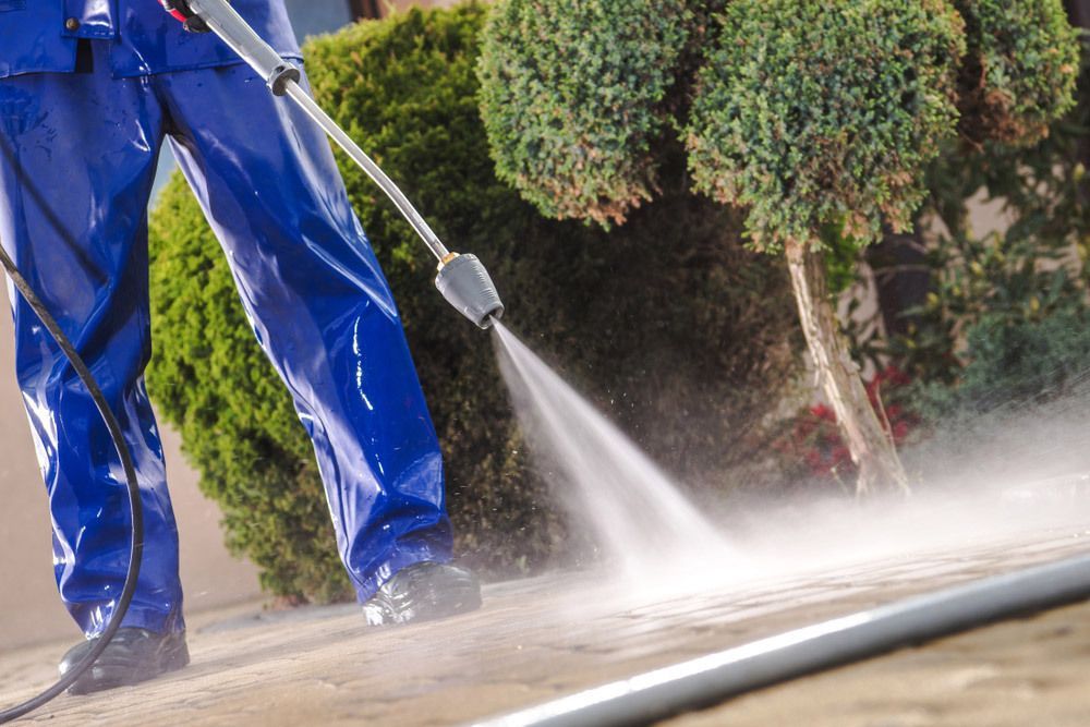 A Man Is Using A High Pressure Washer To Clean A Sidewalk — Gibbo’s Lawns & Property Maintenance In Anna Bay, NSW