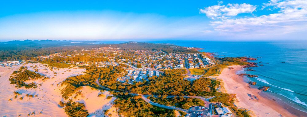An Aerial View Of A Beach With A City In The Distance — Gibbo’s Lawns & Property Maintenance In Anna Bay, NSW