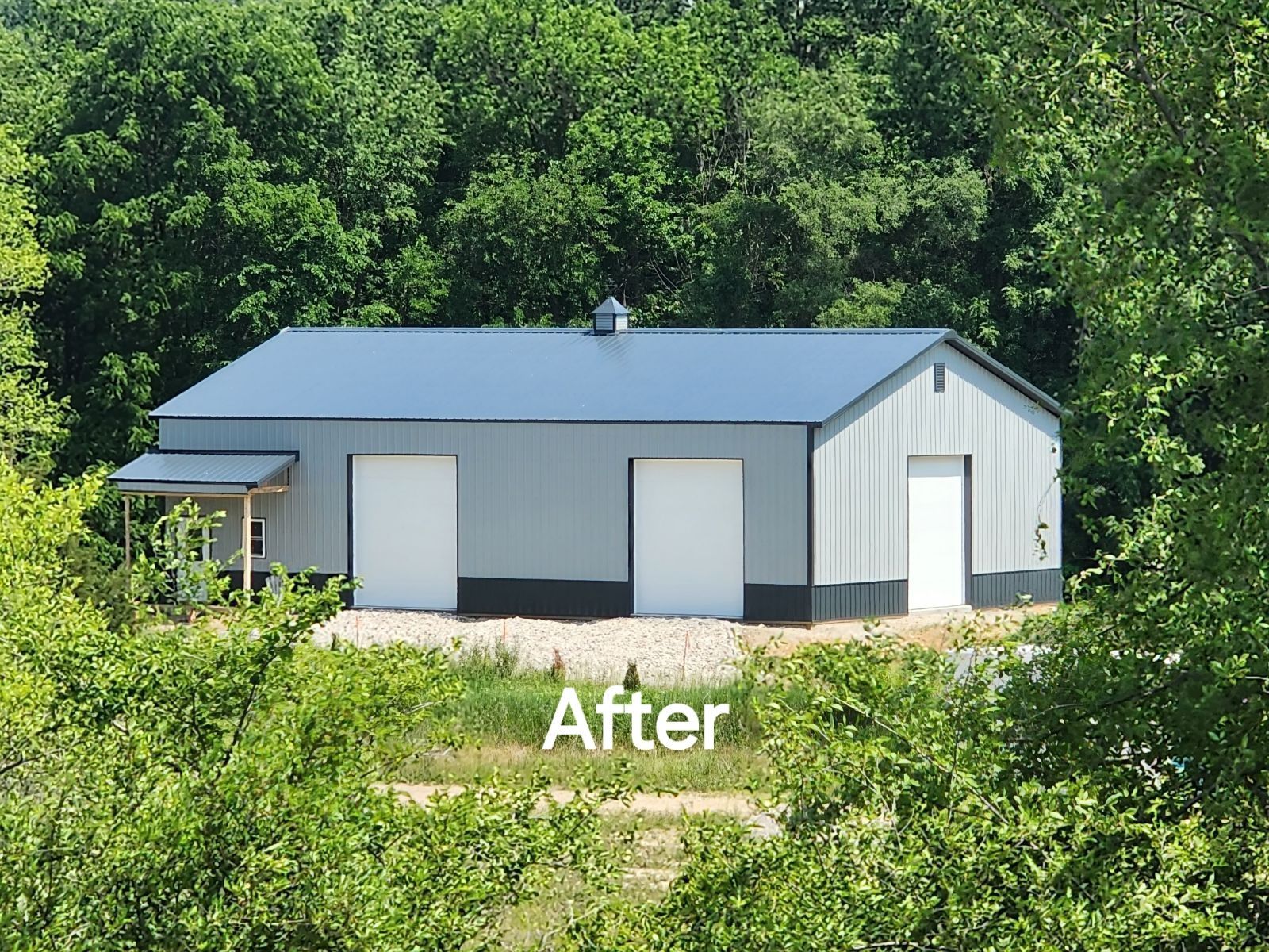 A large building with a blue roof and white doors is surrounded by trees.
