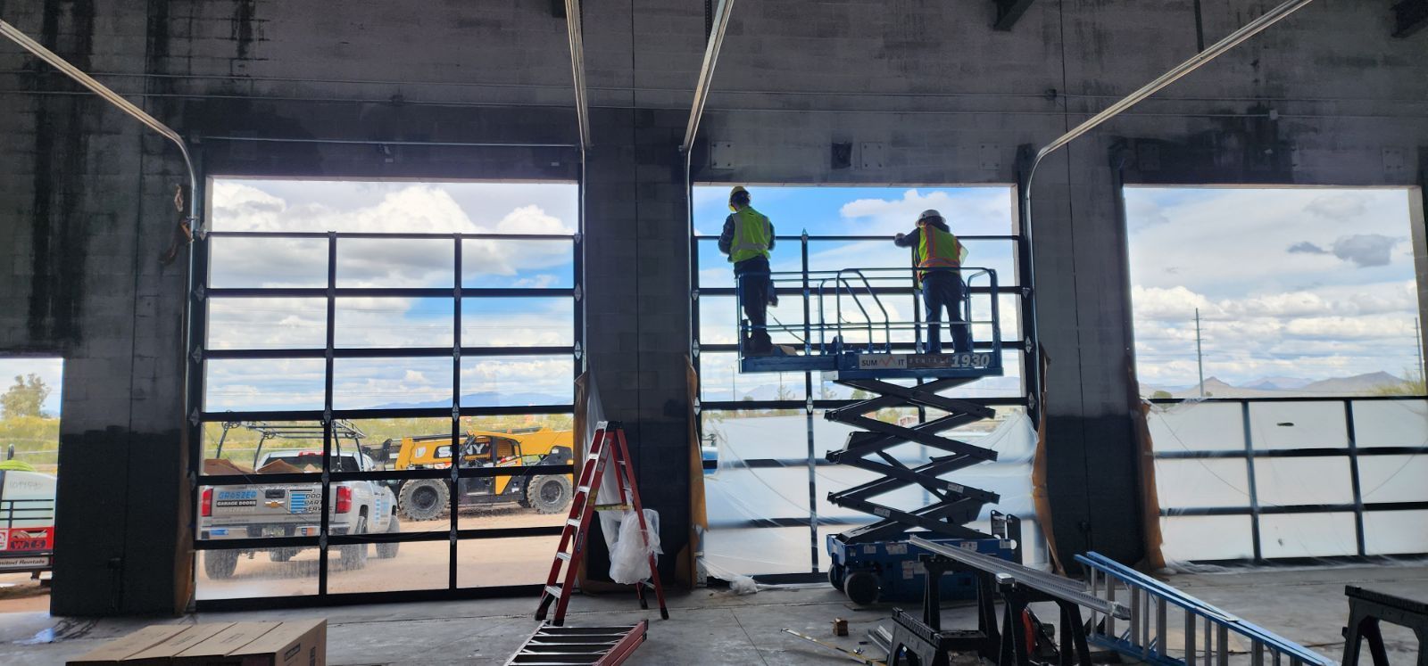 A couple of men are working on a garage door.