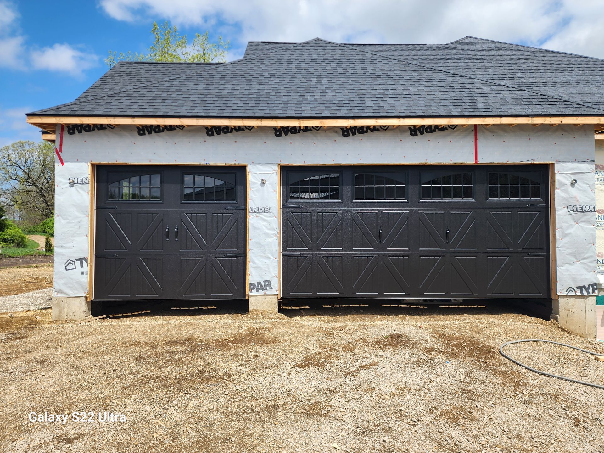 A garage door is being installed on the side of a house under construction.