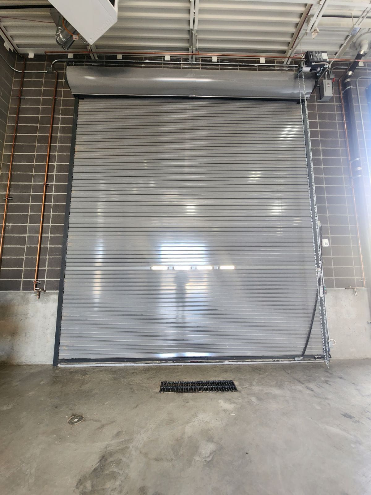 A large metal garage door is open in a warehouse.