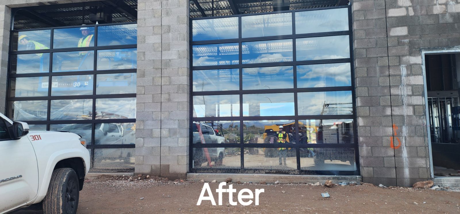 A white truck is parked in front of a building under construction.