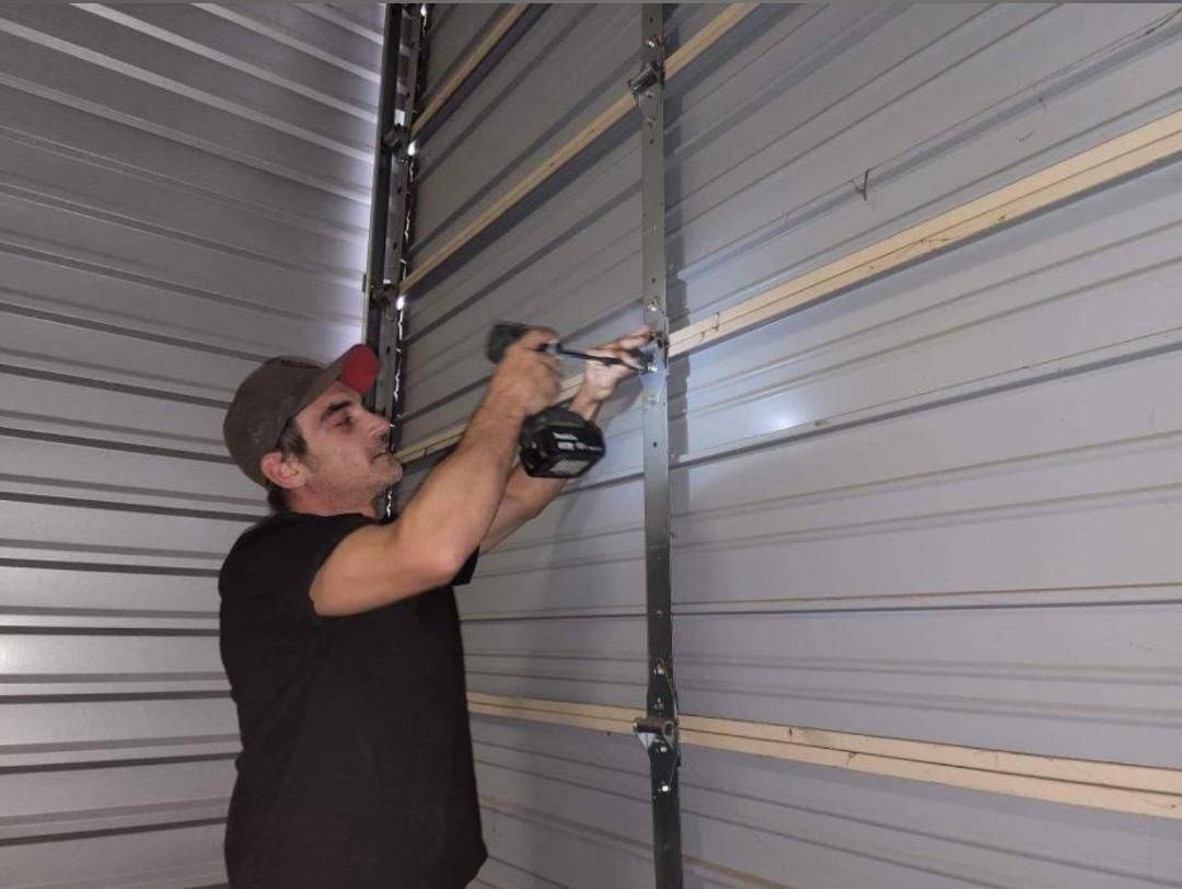 A man is working on a garage door with a drill