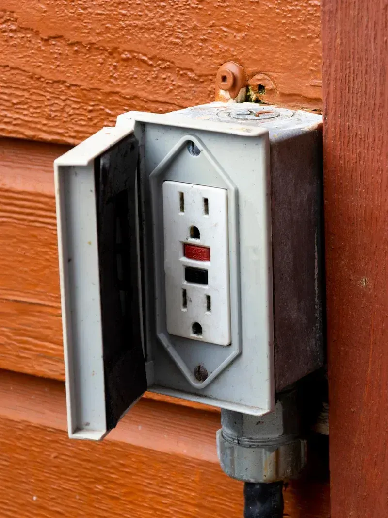 An outdoor electrical outlet with a red light on it