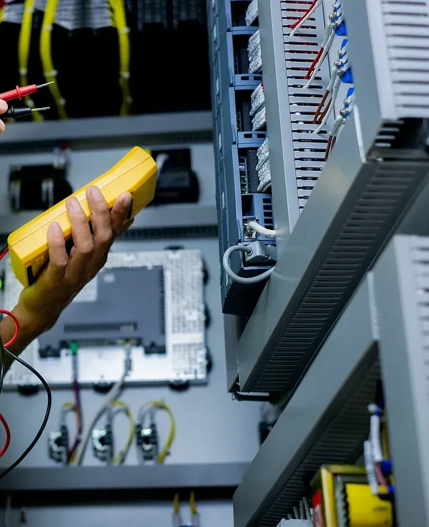 A person is using a multimeter to test a circuit board.