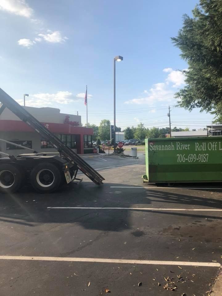 A dumpster is sitting in a parking lot next to a truck.