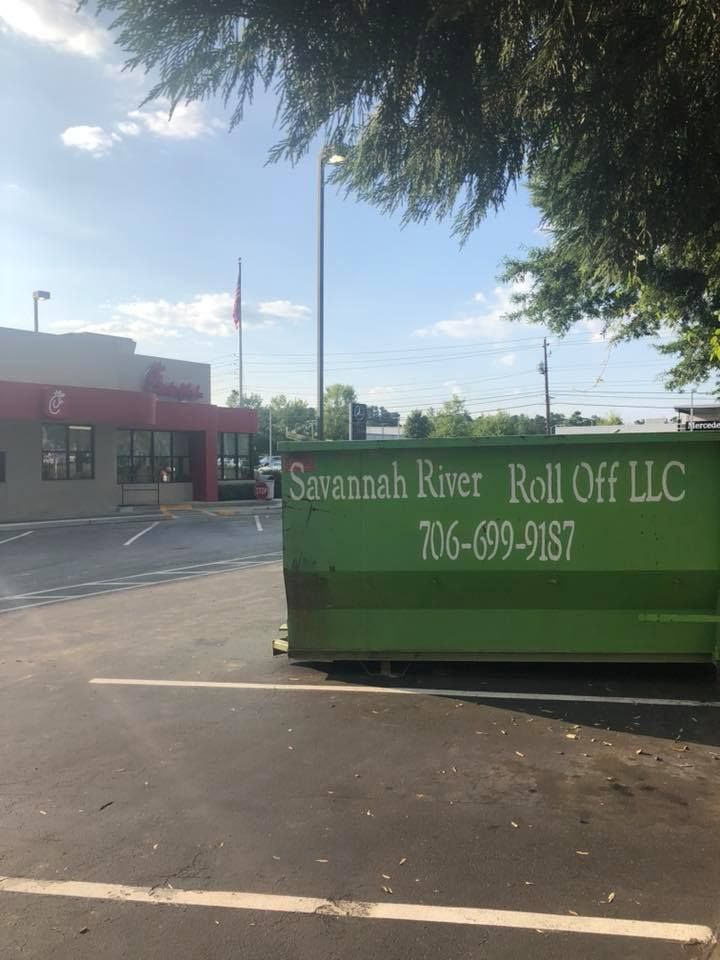 A green dumpster in a parking lot that says savannah river roll off llc