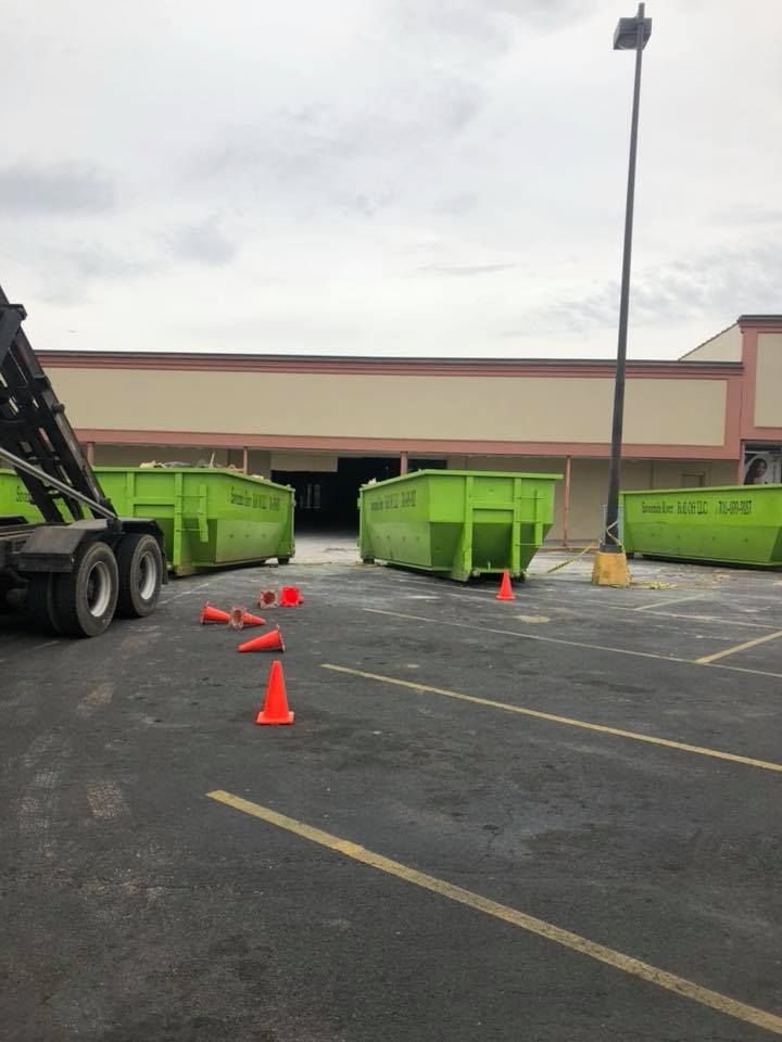 A dumpster is sitting in a parking lot next to a building
