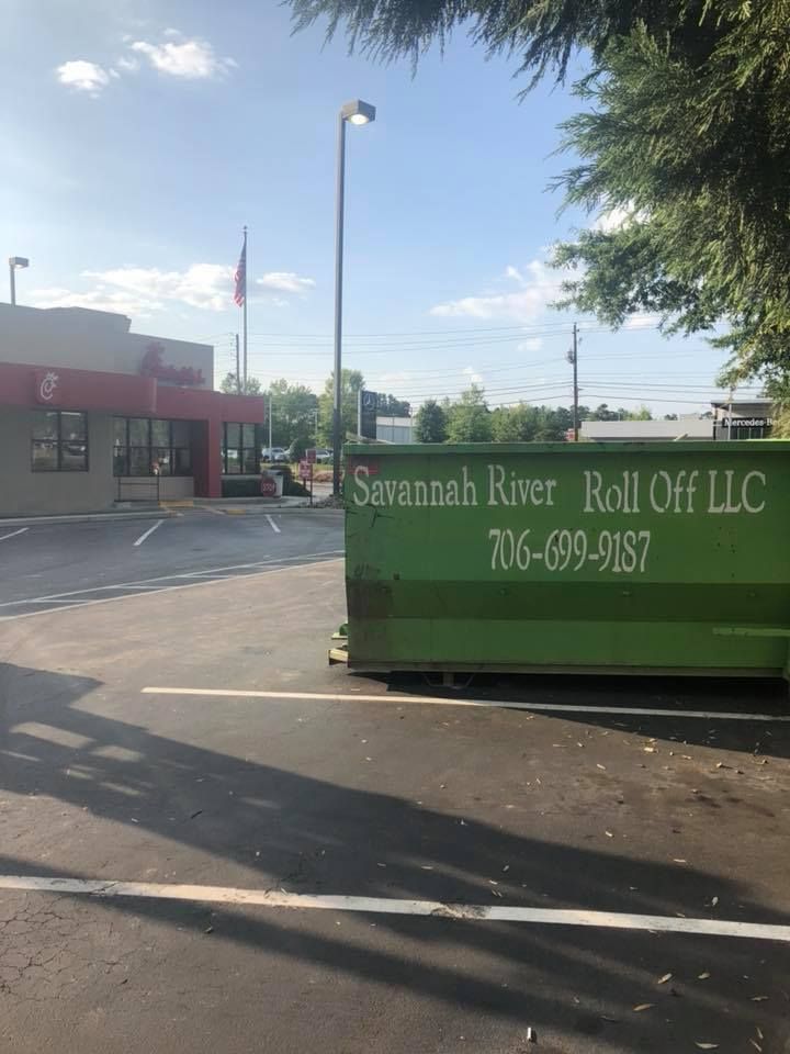 A green dumpster from savannah river roll off llc is parked in a parking lot
