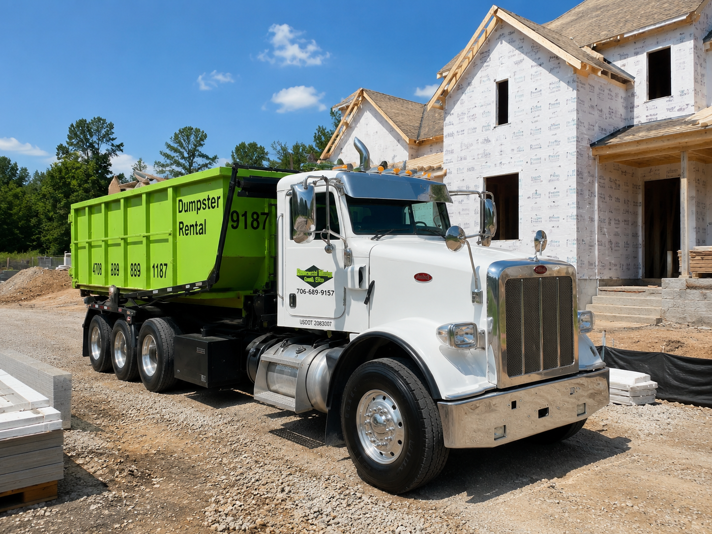 A green dump truck is parked on the side of the road.