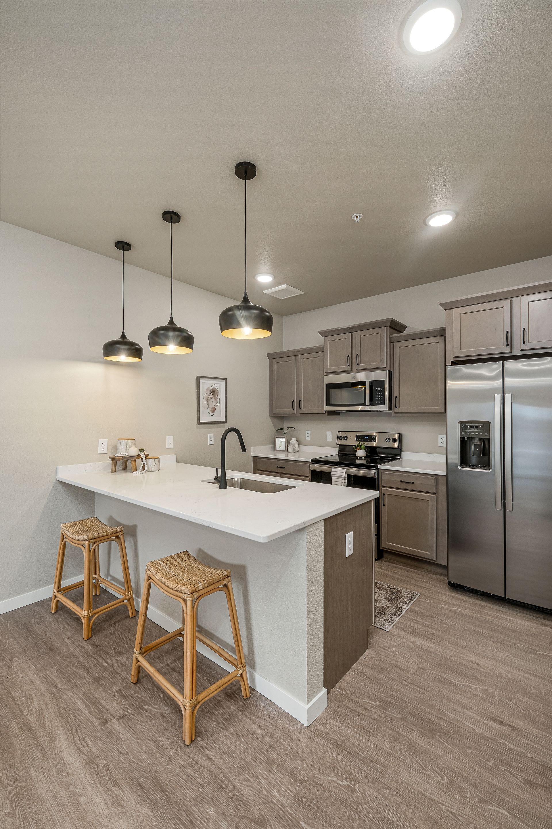 A kitchen with stainless steel appliances and a large island with stools.