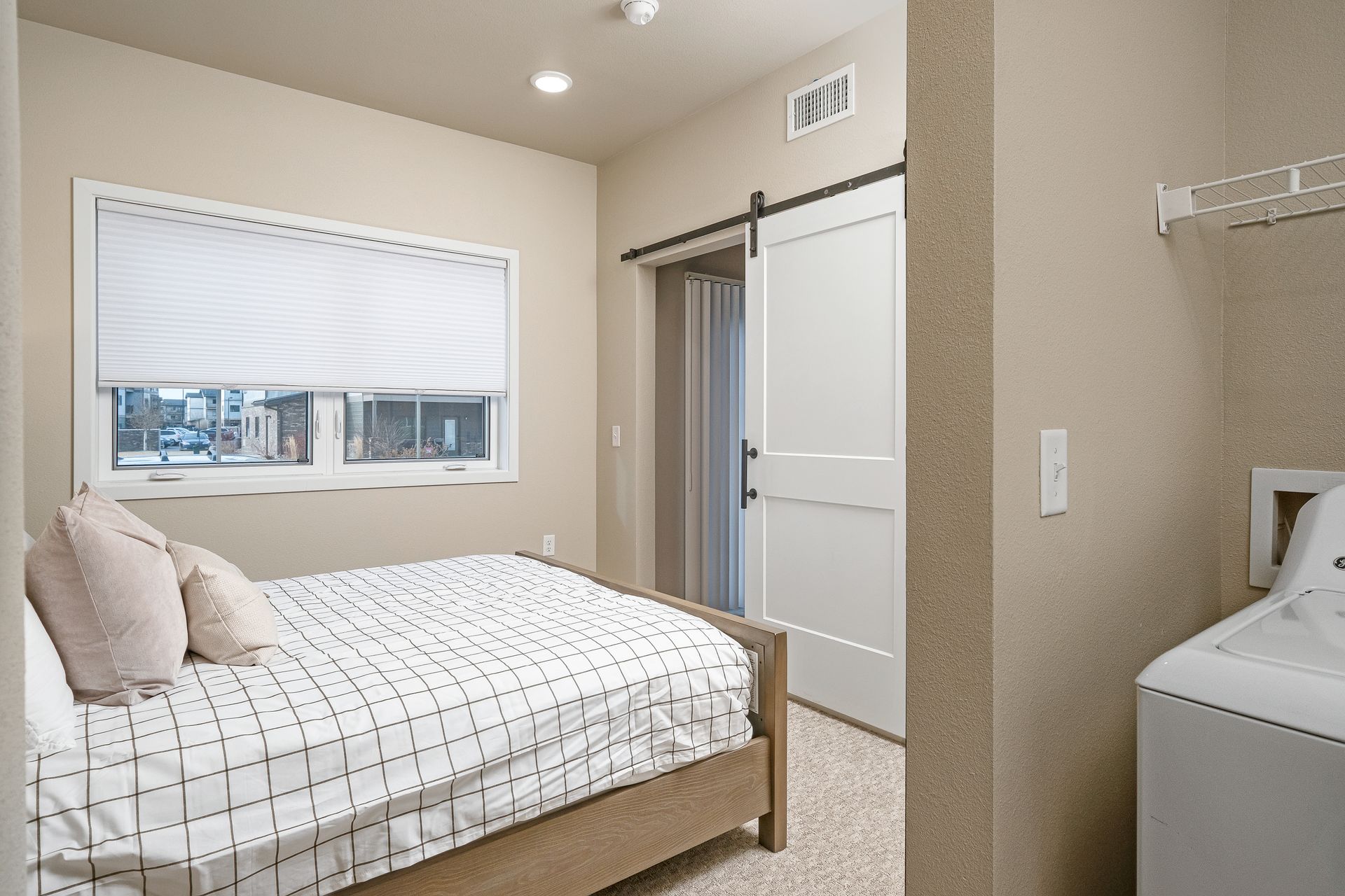 A bedroom with a bed and a washer and dryer.
