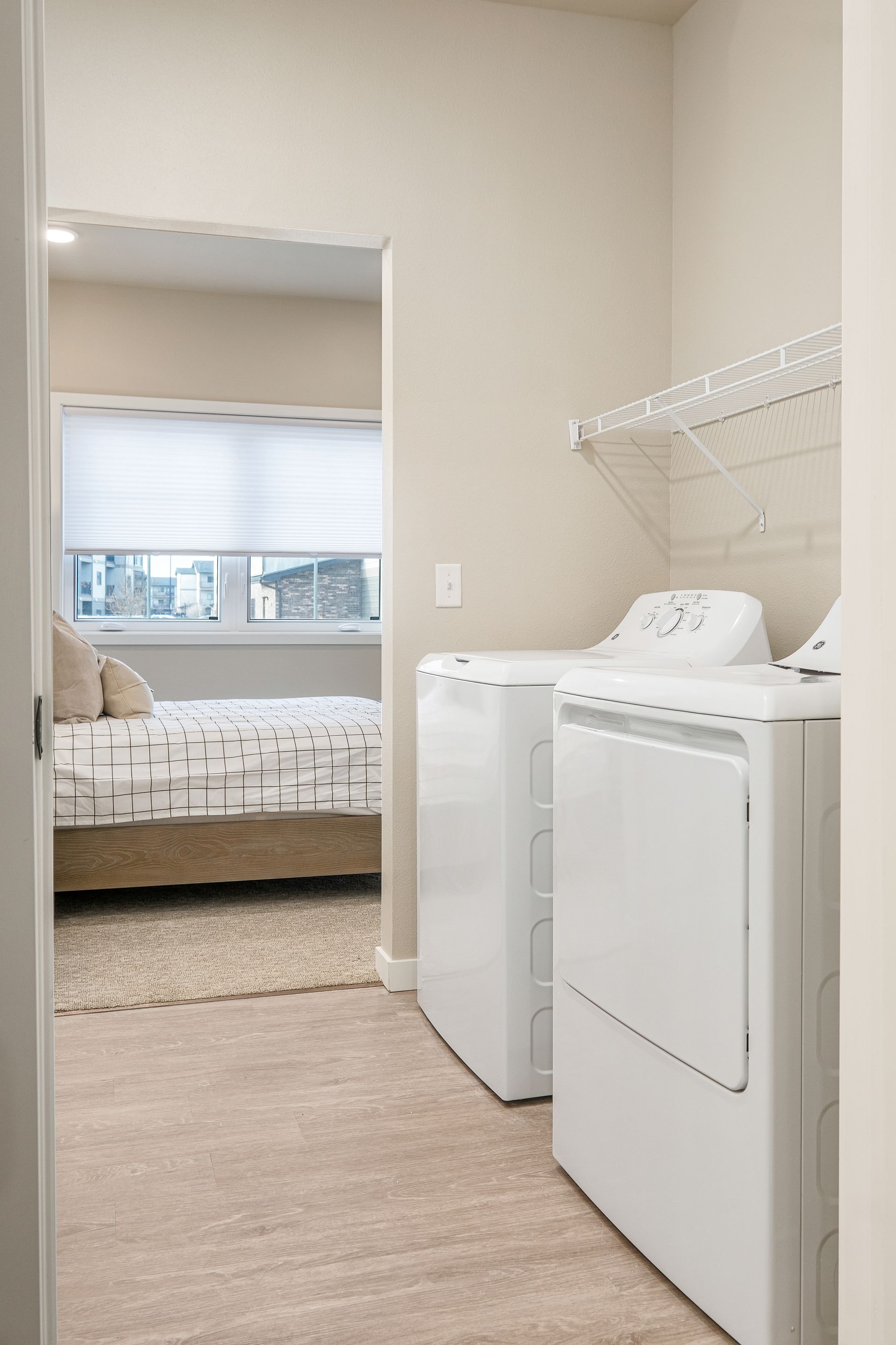 A laundry room with a washer and dryer next to a bedroom.
