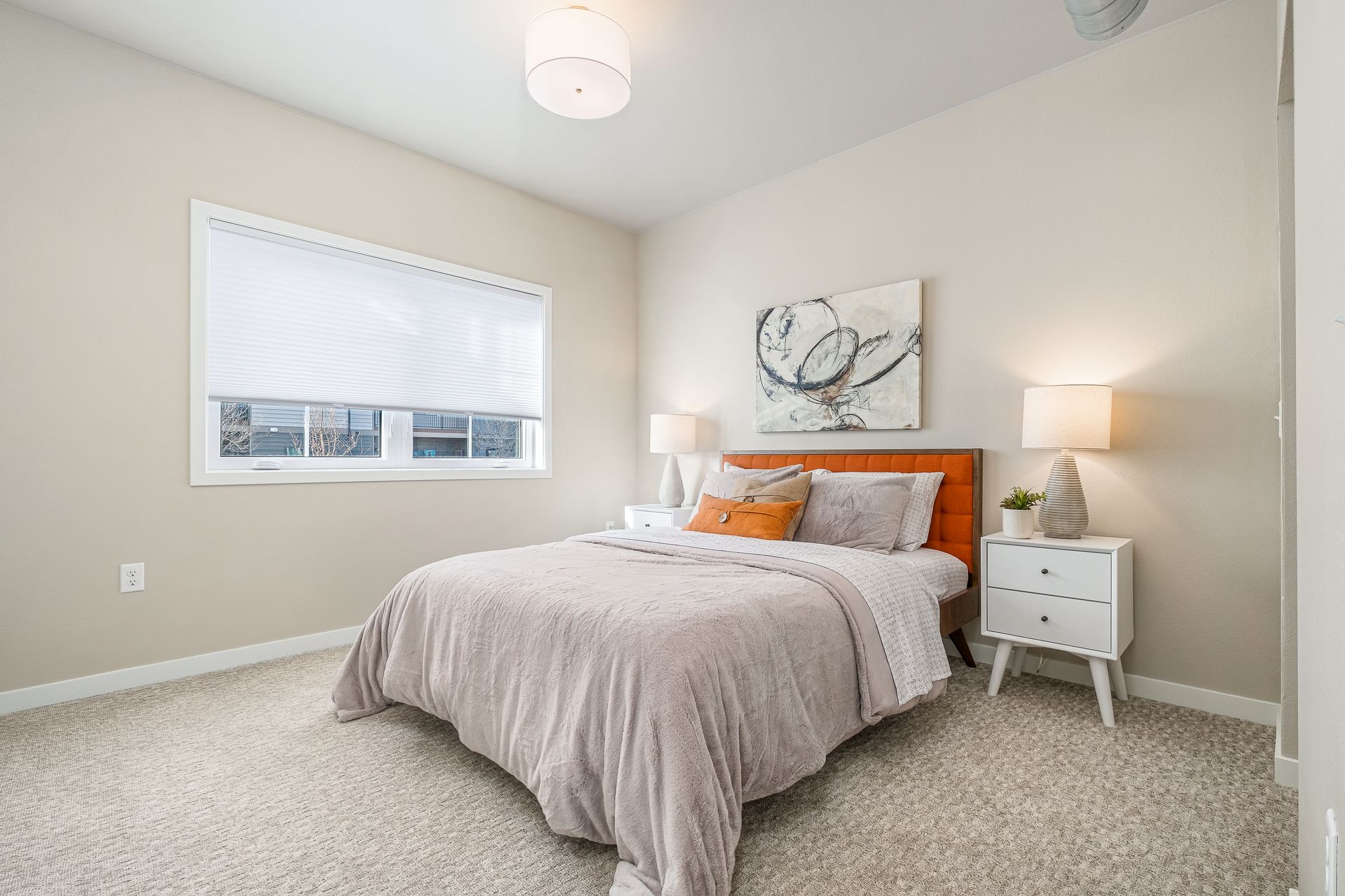 A bedroom with a bed , nightstand , lamps and a window.