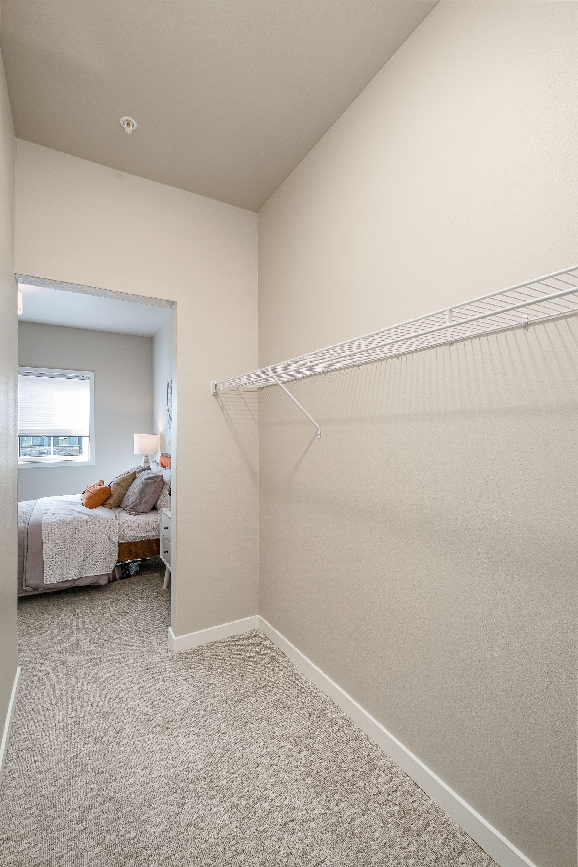 A walk in closet in a bedroom with a bed and a window.