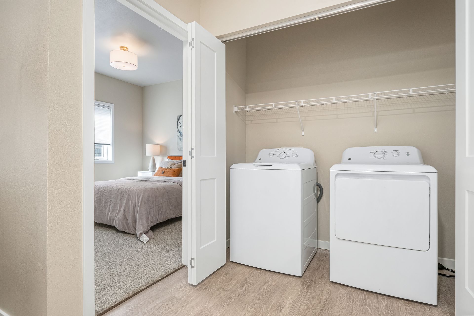 A laundry room with a washer and dryer next to a bedroom.