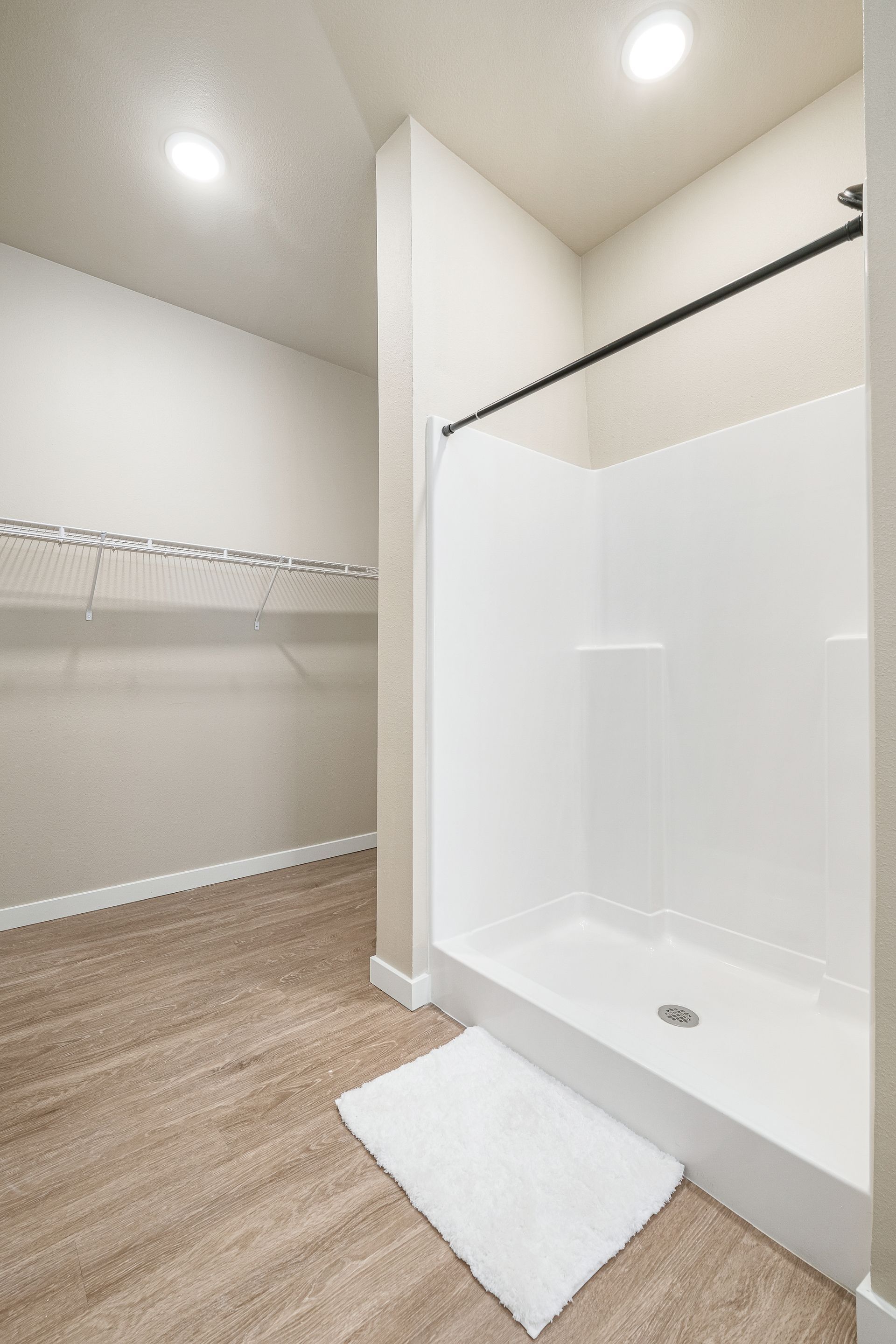 A walk in closet with a shower and a rug on the floor.