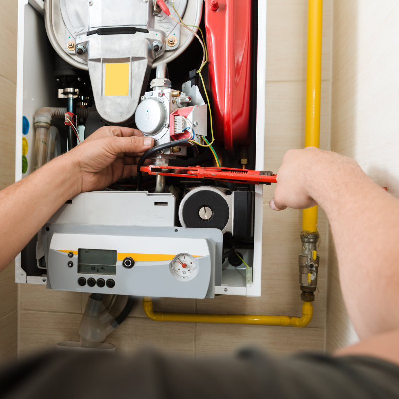 a man is fixing a boiler with a wrench .