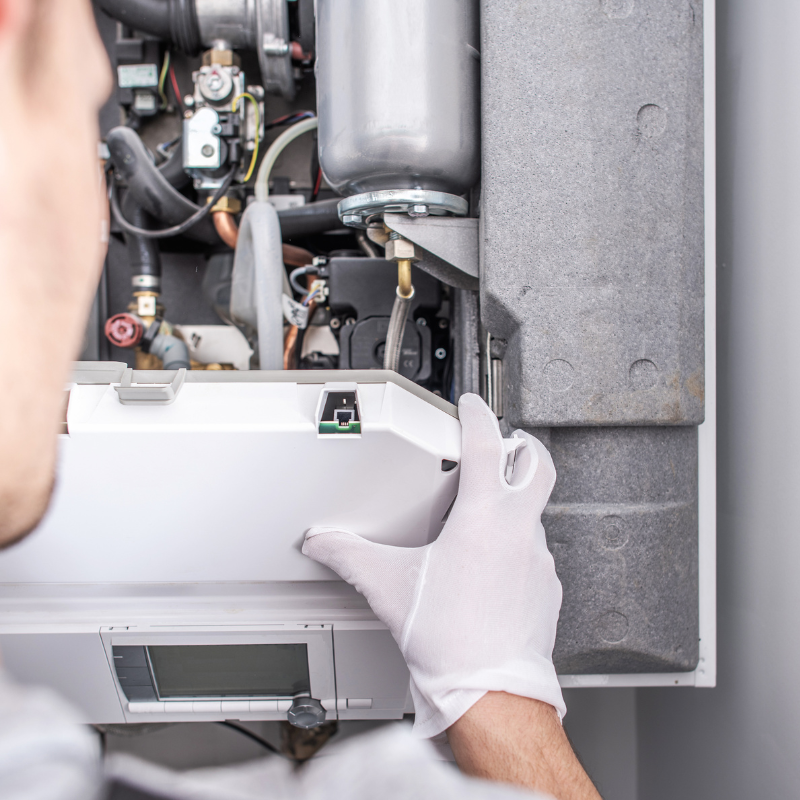 a man wearing white gloves is working on a boiler .