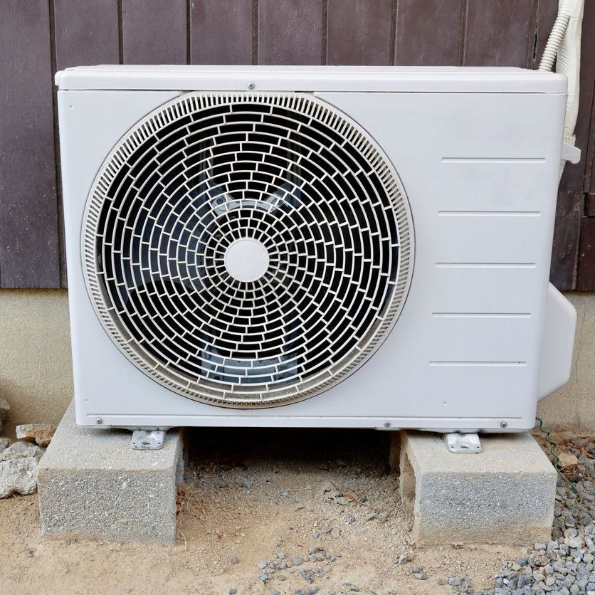 a white fan is sitting on concrete blocks outside of a building .