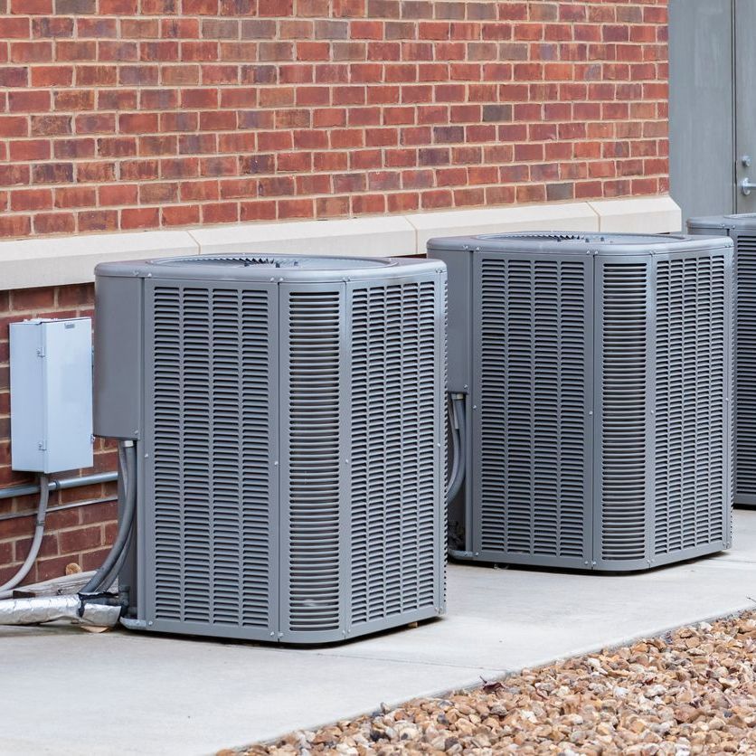 two air conditioners are sitting outside of a brick building .