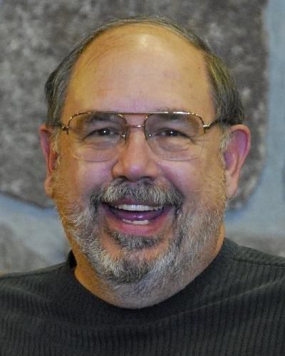 A man with glasses and a beard is smiling for the camera.