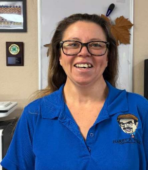 A woman is smiling in front of a cartoon of a man in a suit and tie.