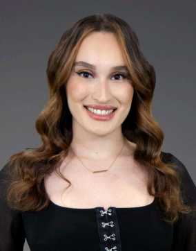 A woman is smiling in front of a cartoon of a man in a suit and tie.