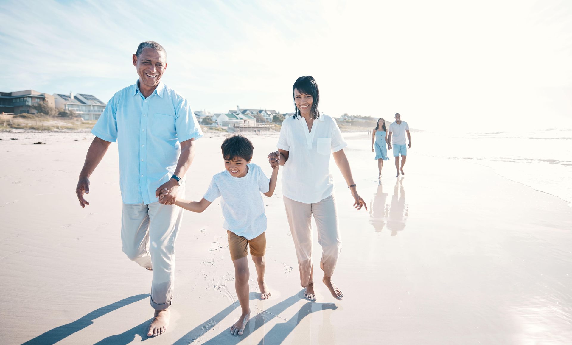 A family is walking on the beach holding hands.