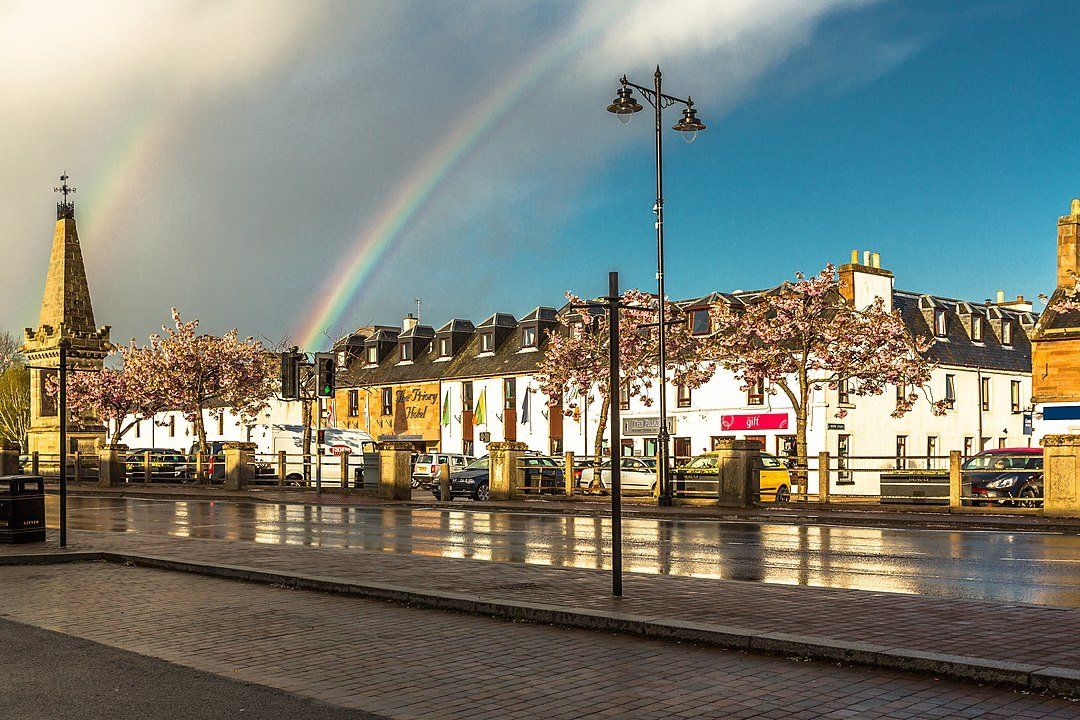 There is a rainbow in the sky over a city street.