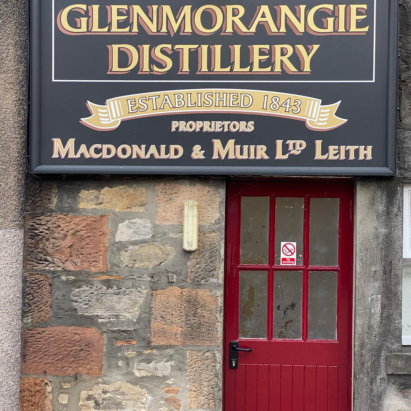 A sign for glenmorangie distillery is above a red door